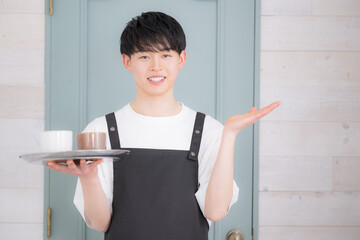 アルバイトやパート、カフェで働く若い20代の男性　求人や採用のイメージ　いらっしゃいませ！カメラ目線