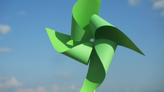 renewable energy concept vertical video. green paper pinwheel in hands against blue sky. World Environment Day. Recycling symbol. circular economy concept for environmental sustainability 