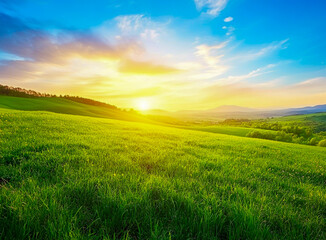 Fototapeta premium Stunning spring scenery with mountains and green meadows bathed in the golden light of sunrise or sunset.