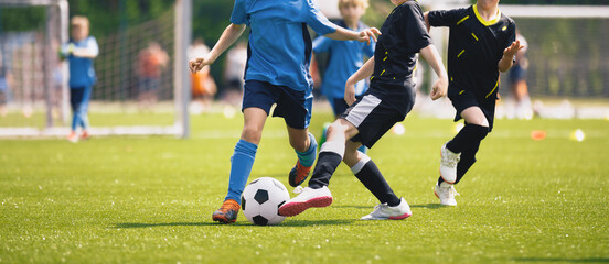 Happy kids compete in football game. Young boys playing soccer game. Kids having fun in sport. Running soccer players. Competition between players running and kicking football ball. Football school