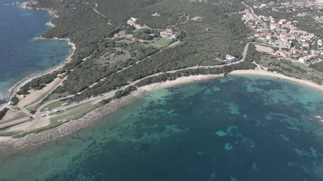 Drone footage of Rena di Levante on Capo Testa, Sardinia, Italy, in summer, showcasing white sandy beach, turquoise waters, coastal dunes, and stunning Mediterranean scenery under clear skies.