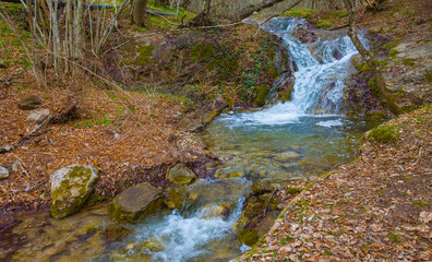 waterfall on small mountain river rushing through canyon