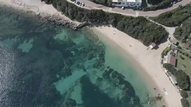Drone footage of Rena di Levante and crystal-clear water on Capo Testa, Sardinia, Italy, in summer, showcasing golden sand, turquoise sea, rolling dunes, and stunning Mediterranean scenery.