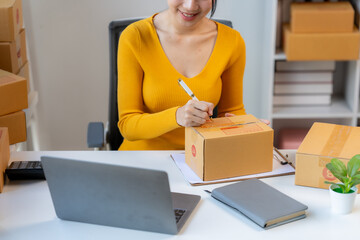 Processing Orders: A smiling woman entrepreneur meticulously prepares packages for shipment in her...