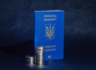 Passport of Ukraine near stacks coins on dark blue background. Problems of migration, war,...