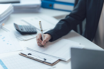 Focused on the Task: A businesswoman diligently completes her paperwork, her hand writing intently...