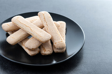 Italian biscuits ladyfingers savoiardi on black slate background. Copy space