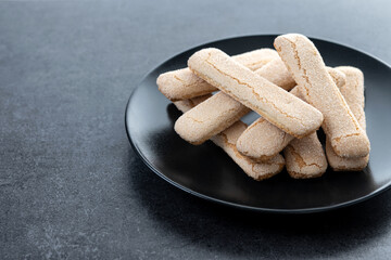Italian biscuits ladyfingers savoiardi on black slate background. Copy space