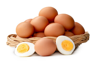Large group of raw brown chicken eggs and peeled cooked or boiled eggs with egg yolk in two halves in stack in wicker basket isolated on white background with clipping path