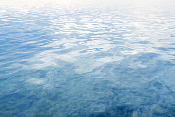 Tranquil scene of a calm body of water, with gentle ripples and reflections of the sky.
