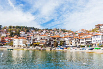 Obraz premium Captivating view of Ohrid lakeside town showcasing traditional house, colorful boats, and serene waters.