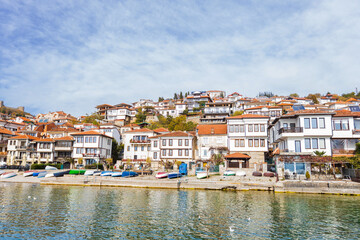 Fototapeta premium Captivating view of Ohrid lakeside town showcasing traditional house, colorful boats, and serene waters.