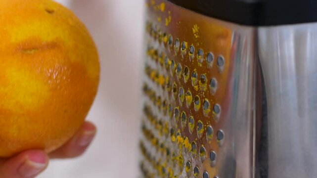 Top view of hand holding an orange and using zester to make orange zest