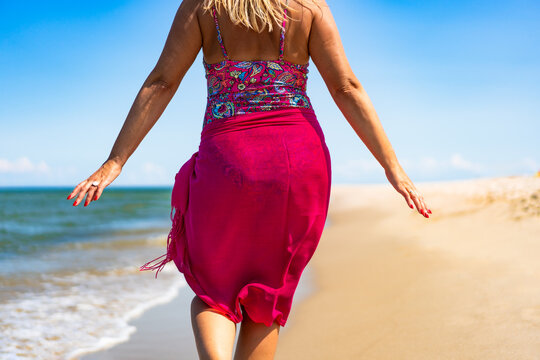 Beautiful middle aged woman tourist on beach holidays on sunny day. Back view, close-up for back, buttocks - Powered by Adobe