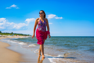 Happy middle aged woman tourist on beach holidays on sunny day. Front view