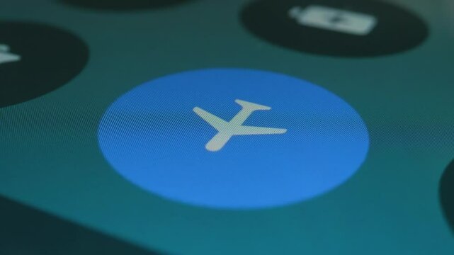 On the screen of a modern smartphone, a finger presses the icon to turn on and off flight mode. Closeup. Macro. Shallow depth of field