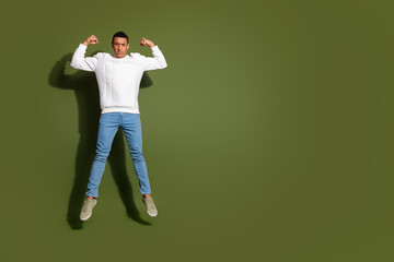 Young man with afro descent poses confidently in white sweater against khaki background, displaying...