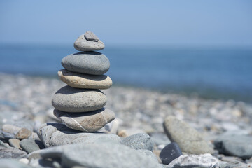 Smooth pebbles on the beach against the background of the sea and sunlight, creating a side effect on the water. Balancing rocks on a pebble beach during sunset. High quality photo