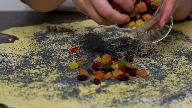 A woman prepares a cruffin with raisins and candied fruits. Rolls the dough cruffin. Tools and ingredients are laid out on the table.