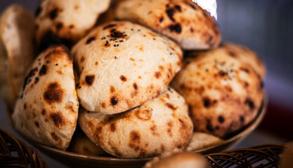 Freshly baked traditional flatbreads (lepinje) stacked in a bowl, featuring a golden-brown crust with charred spots, perfect for culinary or bakery themes.