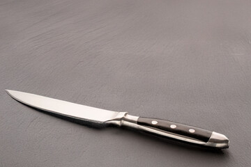 Generated Image. One metal knife on a slate stone, close-up, isolated on a white background.