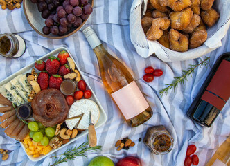 Top view of aesthetic picnic outdoors setup, with wine bottles, fruits and snacks. Picnic food...