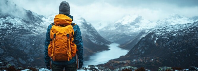 Young traveler and backpacker bask in the awe-inspiring beauty of the mountainous terrain, valley landscapes, and rivers. A solitary globetrotter man wanders alone through nature