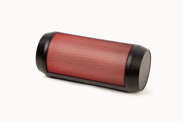 Red portable wireless speaker isolated on white background. Mobile loudspeaker red color with ribbed texture and push control buttons.Horinzontal position.Close-up.