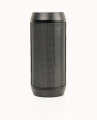 Black portable wireless speaker isolated on white background. Mobile loudspeaker black color with ribbed texture and push control buttons.Vertical position.Close-up.