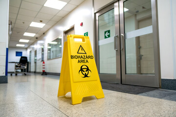 A warning sign indicates a biohazard area in a hospital corridor, emphasizing safety and caution in potentially hazardous environments.