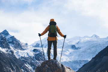 Backpacking woman hiking around the large hanging glacier on high altitude mountain top