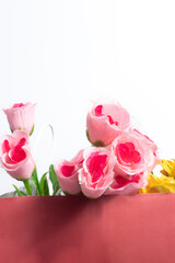 Pink roses and yellow flowers in a red bag on a white background