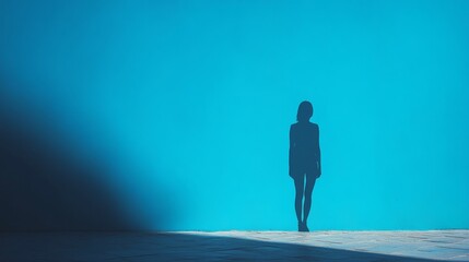 Silhouette of a woman against a striking blue background creating a sense of loneliness and contemplation
