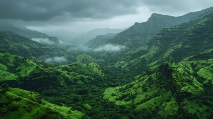 Fototapeta premium A vast mountain range with lush green valleys and misty peaks in the distance