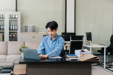 Fototapeta premium pleasant looking successful professional male business accountant learns clients case, works on modern laptop and smartphone.