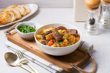 Delicious beef stew with vegetables in a white bowl on white background