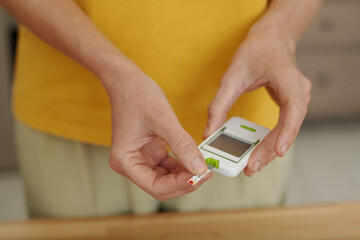 Closeup of female hands holding glucose meter while doing regular checkup for diabetes, copy space