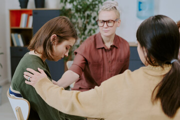 Counselor and two women engaging in supportive therapy session in cozy room with plants and...