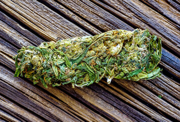 Macro detail of single cannabis bud (mangolope marijuana strain) over wooden dark background