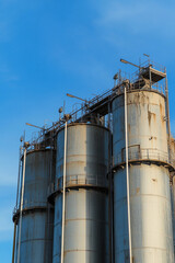 Steel silos against a clear blue sky at sunset
