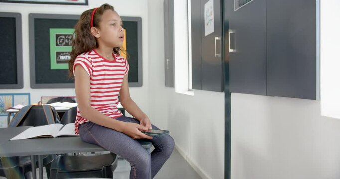 Biracial girl with brown hair sits in a classroom, looking tired with eyes closed, in school