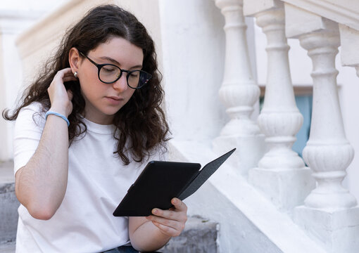 teenager girl reading electronic book outside