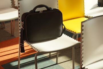 Black work document case on white chair in empty conference room