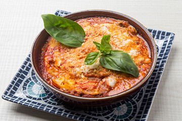 Homemade aubergine lasagna with freshly grated parmesan, basil garnish, resting in rustic ceramic serving dish