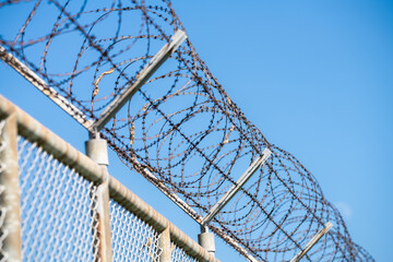 Barbed wire fence symbolizing border control, geopolitical tensions, and restricted freedoms in modern society. Barbed wire border security fence. Barrier border. Boundary security wall. Private area.
