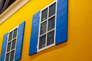 A vibrant yellow building featuring blue shutters adorning the windows