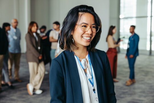 Smiling woman enjoying participation at a workshop with colleagues in the background sharing ideas
