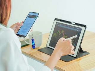 Businessman looking at stock chart on laptop screen. Asian businesswoman working on stocks and investment at home. Close-up of screen showing up and down market and economy chart. Working from home.