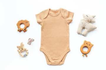 Flat lay with beige baby bodysuit and eco friendly toys on white background, top view