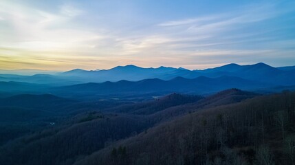 Fototapeta premium Majestic mountain ranges with layered blue ridges and a misty atmosphere, capturing the serene beauty of towering peaks and natural landscapes in the early morning light